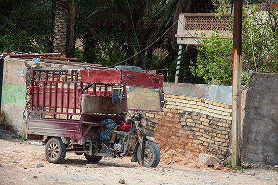 Irak, Karbala. Trojkolowy motocyl transportowy zaparkowany na poboczu ulicy.