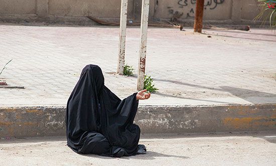 Irak, Karbala. Kobieta zebrzaca na ulicy w centrum miasta.