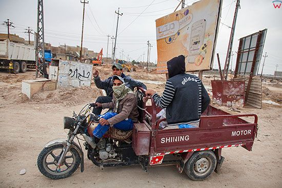 Irak, Karbala. Robotnicy jadacy trojkolowym motocyklem w NW czesci miasta.